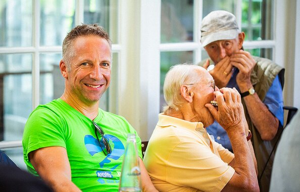Fonds Finanz Geschäftsführer Norbert Porazik und zwei Senioren, die auf der Mundharmonika spielen