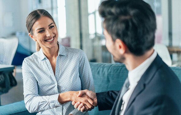 Eine Mitarbeiterin der Fonds Finanz und ein freier Makler reichen sich die Hand