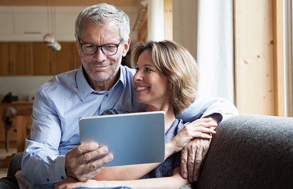 Privatanleger, die zu Hause auf dem Sofa sitzen und Wissenswertes zu Investment-Themen lesen