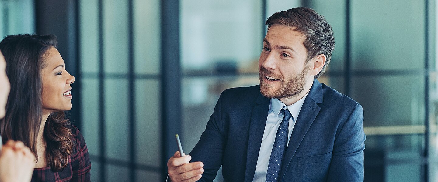 Ein Investmentberater im Gespräch mit zwei Kundinnen zu aussichtsreichen Anlagestrategien