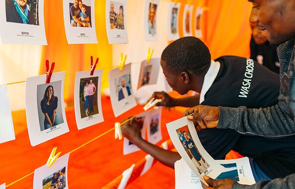 In einem Zelt hängen Helfer im Rahmen des Wunschpatenprogramms der Fonds Finanz Fotos von Paten für die Kinder auf