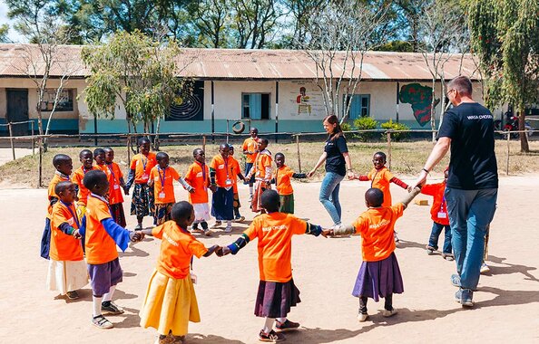 Die CSR-Manager Irmi und Simon beim Spielen mit den afrikanischen Kindern vor einer Schule