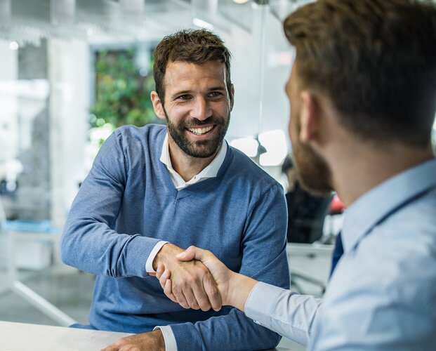 Ein Fonds Finanz Mitarbeiter gratuliert einem Vermittler zum Unterzeichnen der verschiedenen Bestandteile des Vertragspakets