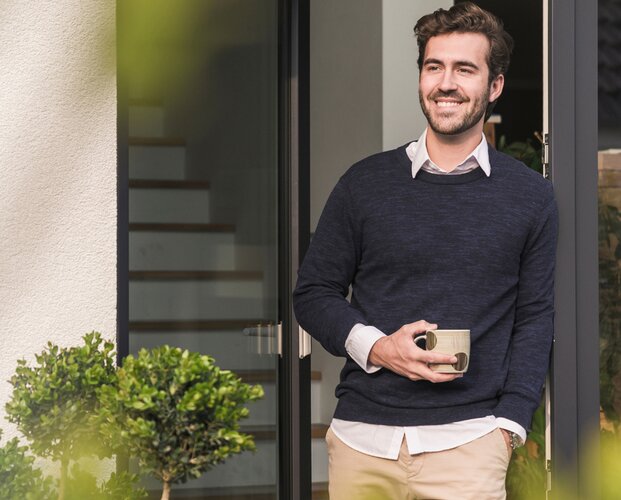 Ein Vermittler, der entspannt einen Kaffee trinkt, nachdem er sich über die Highlights der Vermögensverwaltung ComfortInvest informiert hat