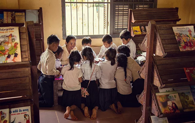 Kinder und eine Lehrerin sitzen um einen Tisch herum