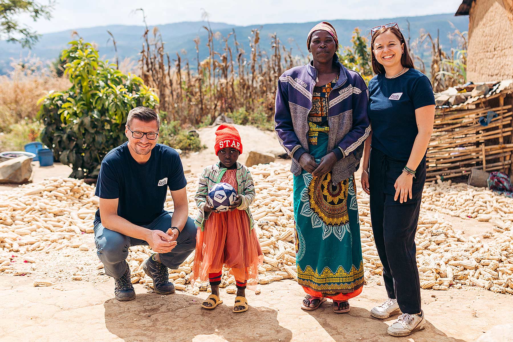 Irmi und Simon vom CSR-Team zu Besuch beim Fonds Finanz Patenkind Graceous und ihrer Großmutter in einem kleinen Dorf in Wasa in Tansania