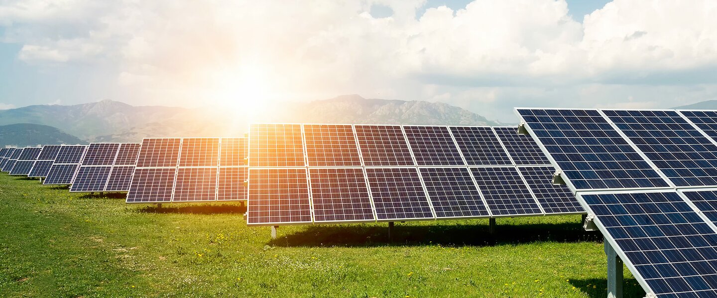 Eine große Photovoltaikanlage, die auf einer grünen Wiese installiert ist und für die Makler Beteiligungen in Form von Finanzanlagen vermitteln