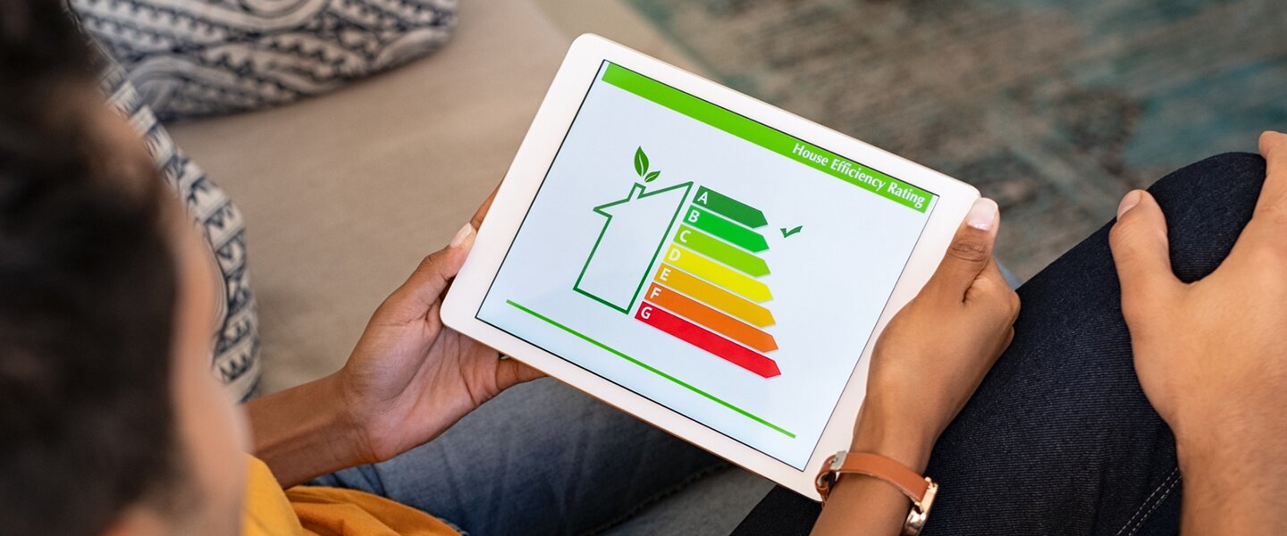 Eine Frau mit iPad in der Hand, auf dem sie mit einem Tool die Energieeffizienz ihres Wohnhauses prüft