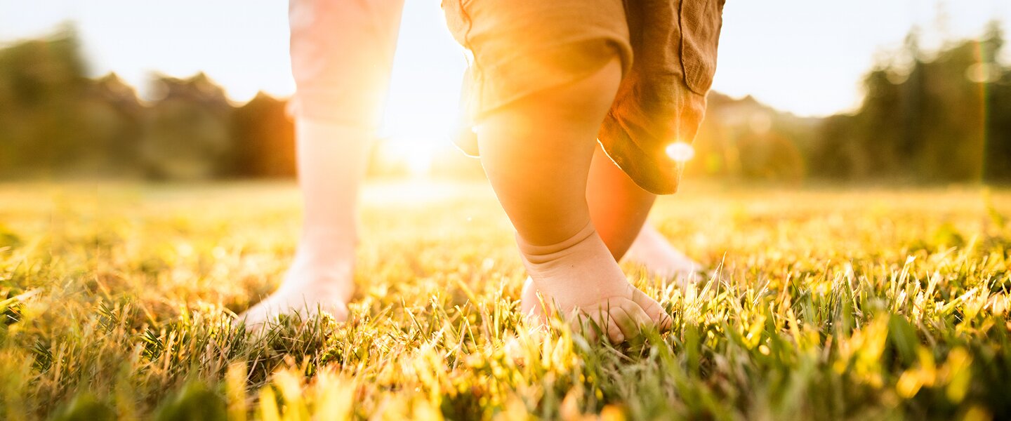 Ein Kind, das mit seinem Vater auf einer grünen Wiese spielt als Imagebild für den Climate Impact Pool, den die Fonds Finanz ins Leben gerufen hat, um sich gemeinsam mit anderen Firmen für das Klima zu engagieren