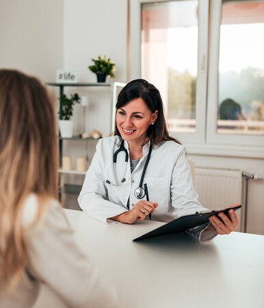 Eine Patientin beim Arzt im Beratungsgespräch zur privaten Krankenzusatzversicherung