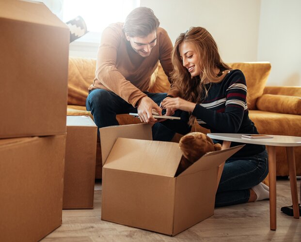 Ein junges Paar beim Auspacken von Umzugskartons in ihrer Wohnung als Mood-Foto für private und gewerbliche Sachversicherungen