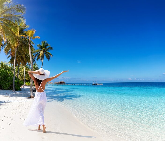 Eine Maklerin am weißen Palmenstrand auf einer Reise, die sie über das Reisebüro FF & Meer vergünstigt gebucht hat