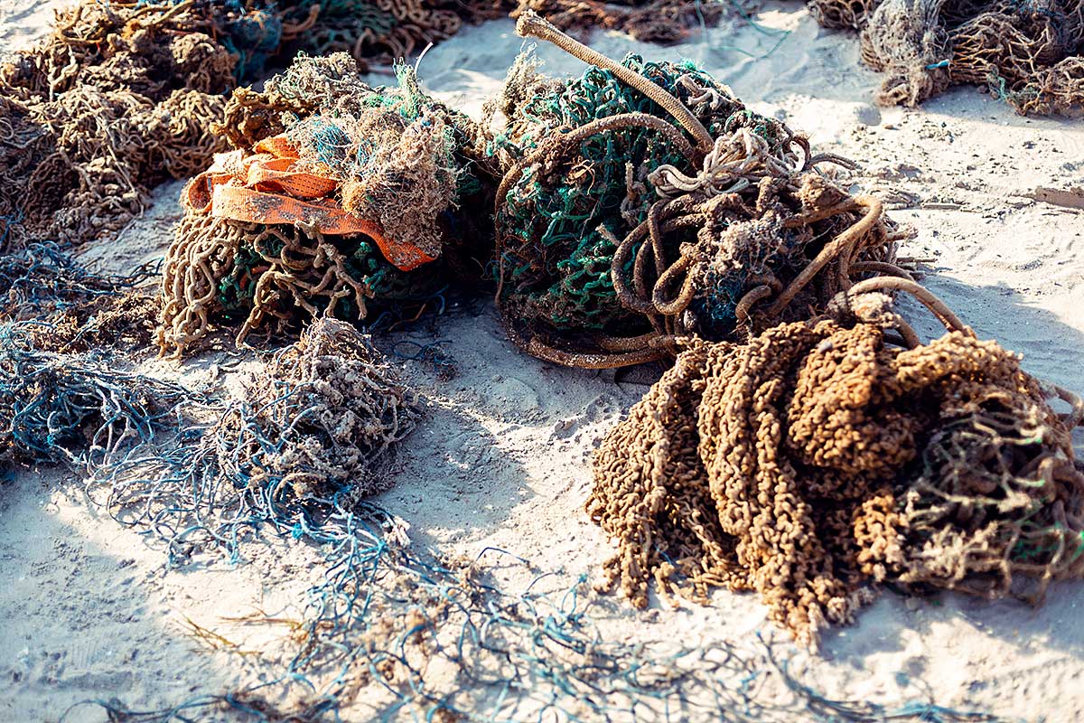 Von Tauchern geborgene, alte und zerrissene Fischernetze am Strand
